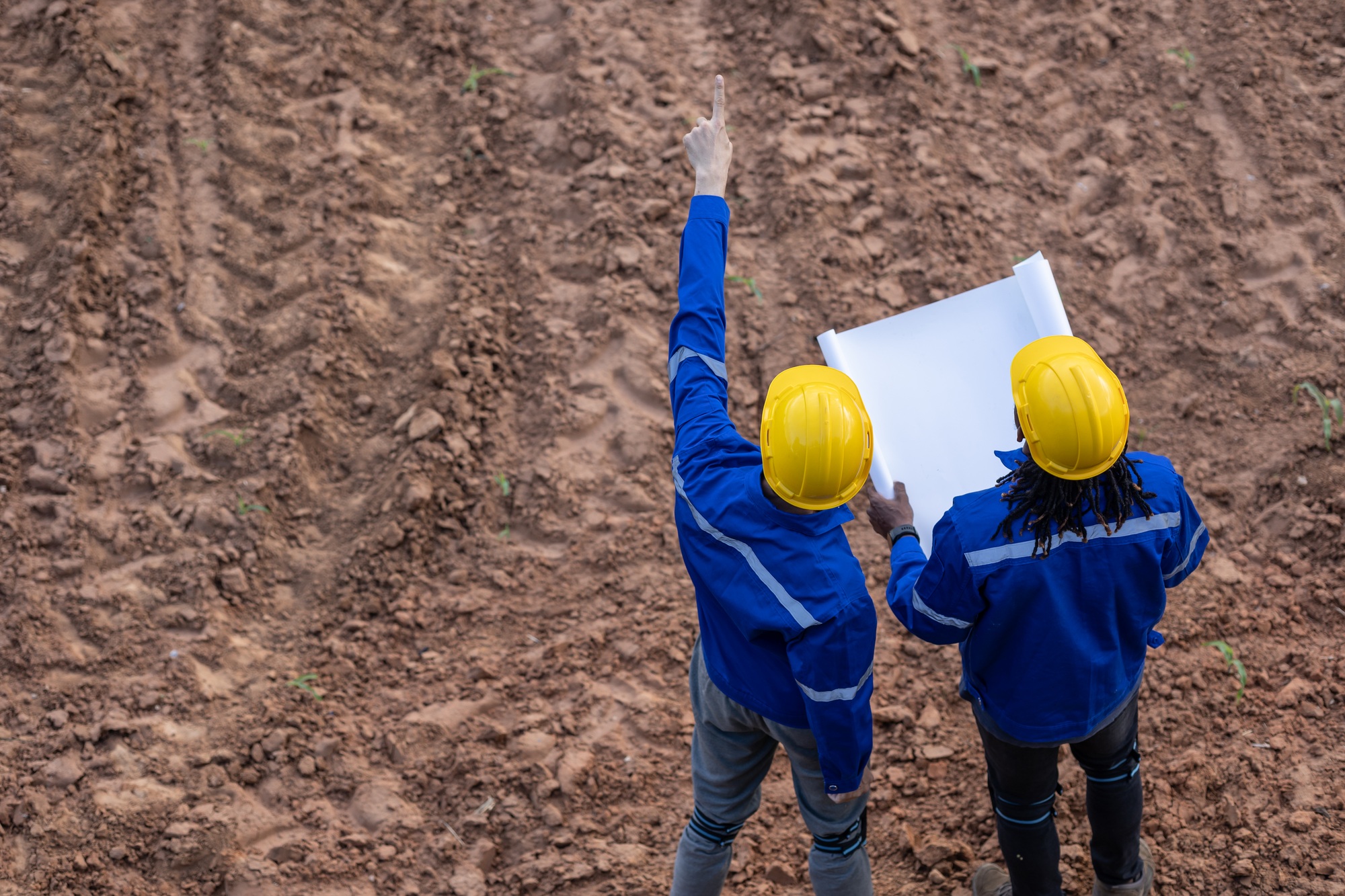 Land surveyor team standing working together at construction field consult study looking landmark